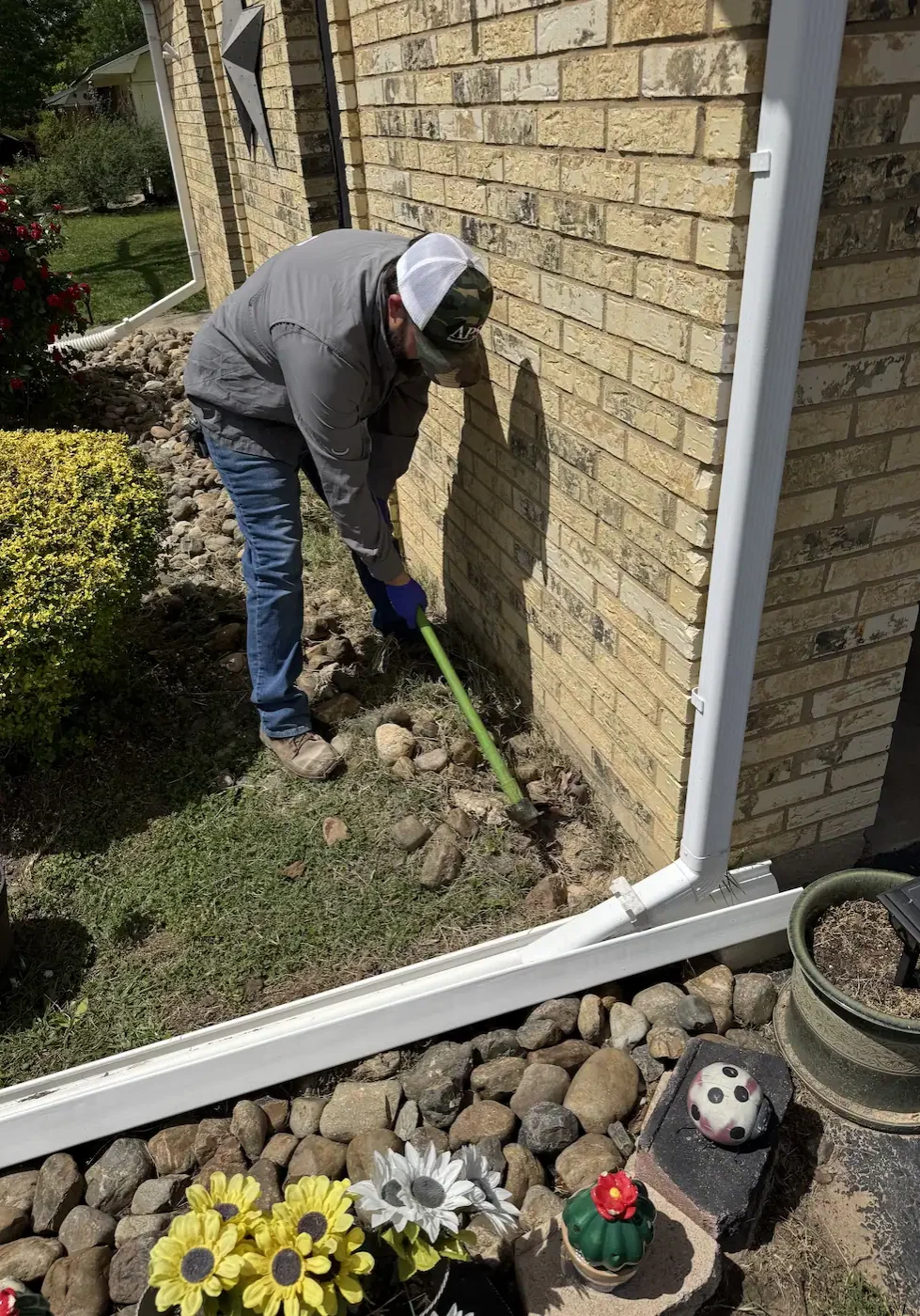 APS Pest Control technician applying termite treatment near a home foundation in East Texas.