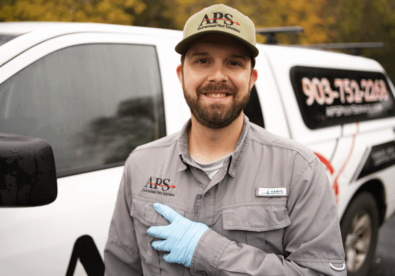 A happy and trustworthy APS technician pointing happily at the APS logo on his uniform.