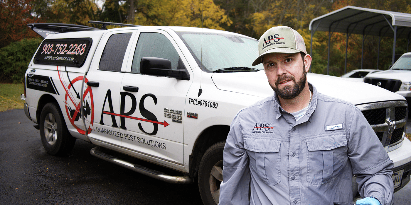 One of the APS technicians standing confidently in front of a service truck, ready to do some pest control.