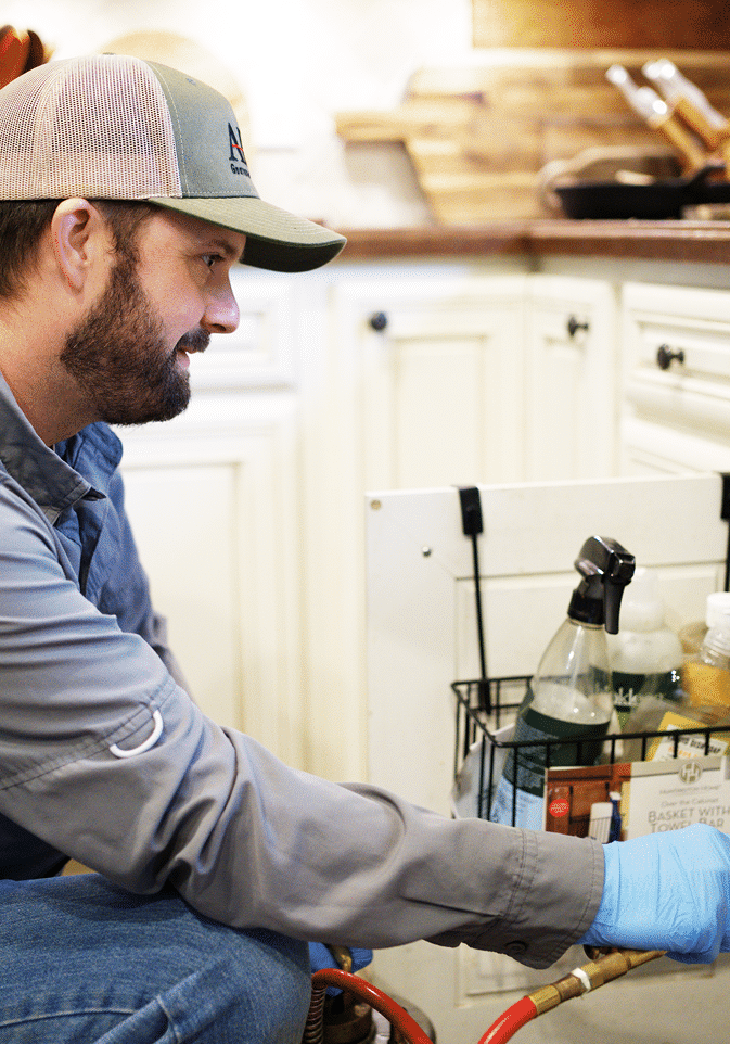 An APS technician doing a treatment in the kitchen after doing a thorough inspection of the whole property.